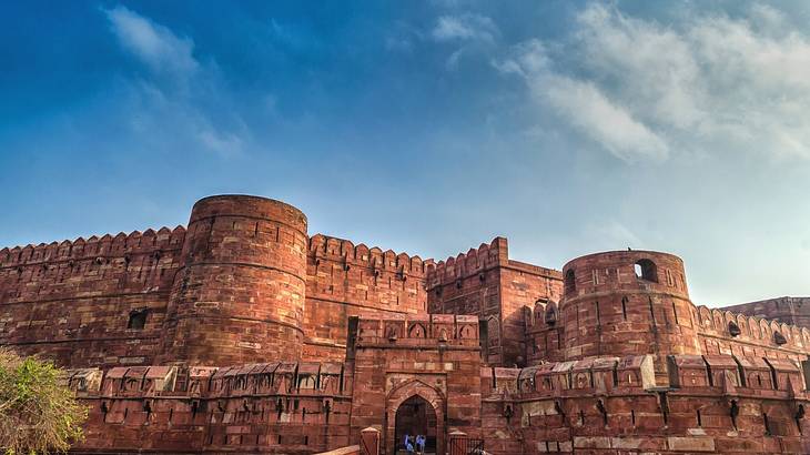 The outside red sandstone buildings of a fort complex against a blue sky