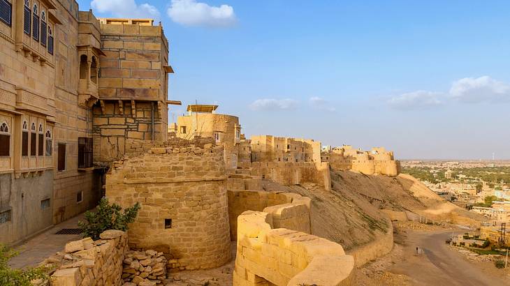 A side view of a massive sandy-coloured fort surrounded by stone walls