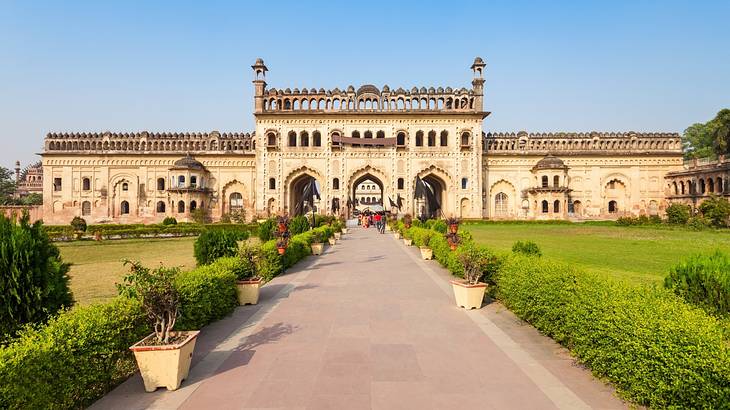 A massive palace complex at the end of a lane surrounded by lush green gardens