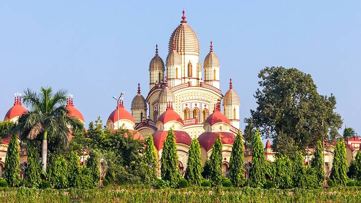 A red and white temple with pointy tops surrounded by lush green trees A red and white temple with pointy tops surrounded by lush green trees