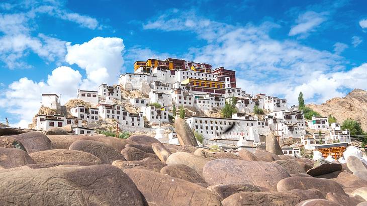 A monastery with multiple buildings on a hill from below and behind rocks