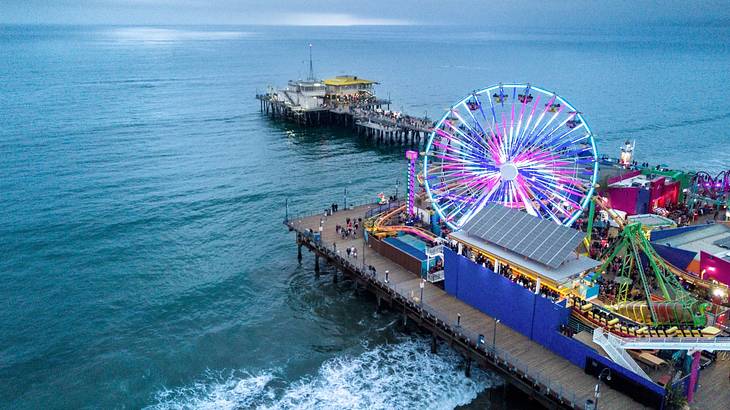 Aerial view of a wooden pier with a colorful amusement park facing the ocean