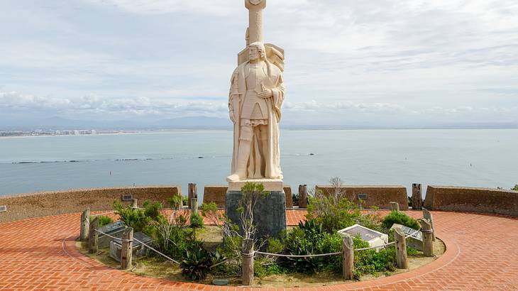 White statue overlooking the ocean with a cloudy sky in the background