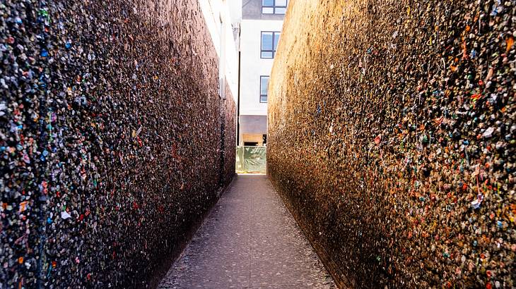 A building at the end of a narrow alley with walls covered with used chewing gum