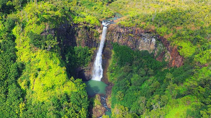 Aerial shot of a waterfall in the middle of a tropical canyon