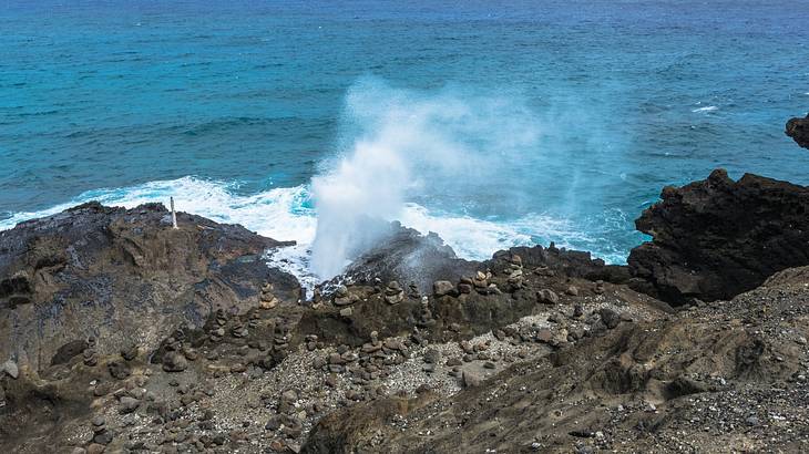 Mist of water getting sprayed out of a blowhole on a rocky coastline