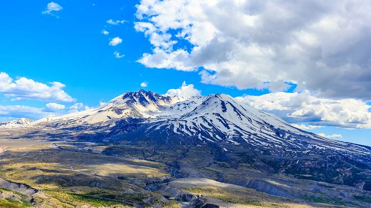 Panoramic view of clouds looming over a volcano covered with snow