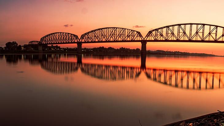Silhouette of a bridge over a tranquil river during a beautiful sunrise