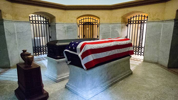 Room with one black casket and the other covered with a white, red, & blue flag