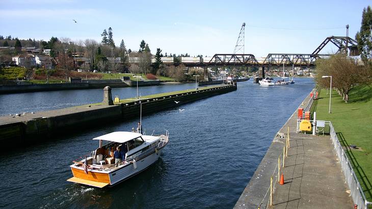 A white boat exiting a canal lock on a sunny day during high tide