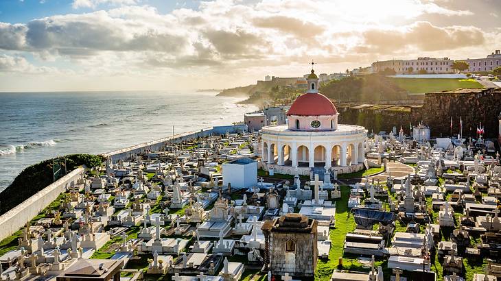 A white dome-shaped chapel in the middle of a cemetery overlooking the ocean