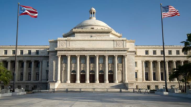 Two white, red, and blue flags standing in front of a magnificent building Two white, red, and blue flags standing in front of a magnificent building