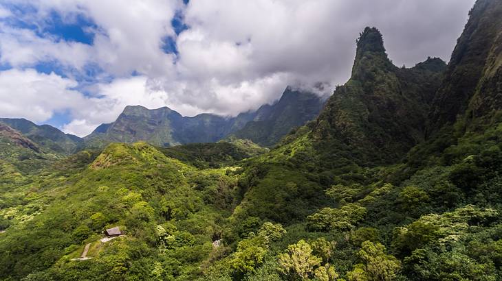 Tall greenery covered mountains in front of a blue sky with clouds Tall greenery covered mountains in front of a blue sky with clouds