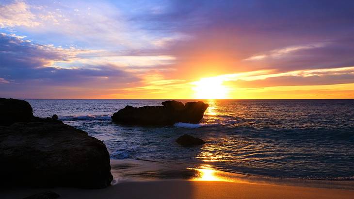 Sunlight reflected in the sand of a shore with large rocks Sunlight reflected in the sand of a shore with large rocks