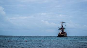 A pirate ship on the ocean in the distance