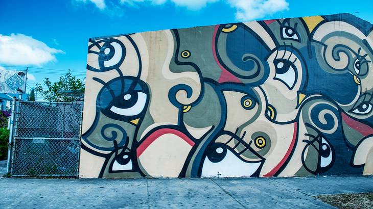 A creative graffiti wall full of eyeballs against a blue sky