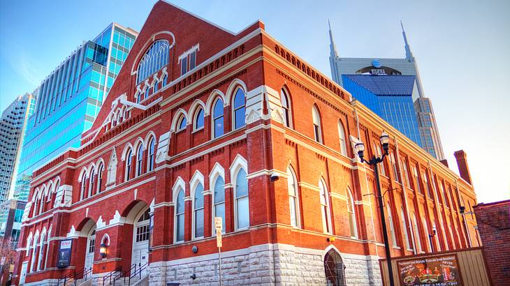 A red brick building with white details, a street in front, and skyscrapers behind it