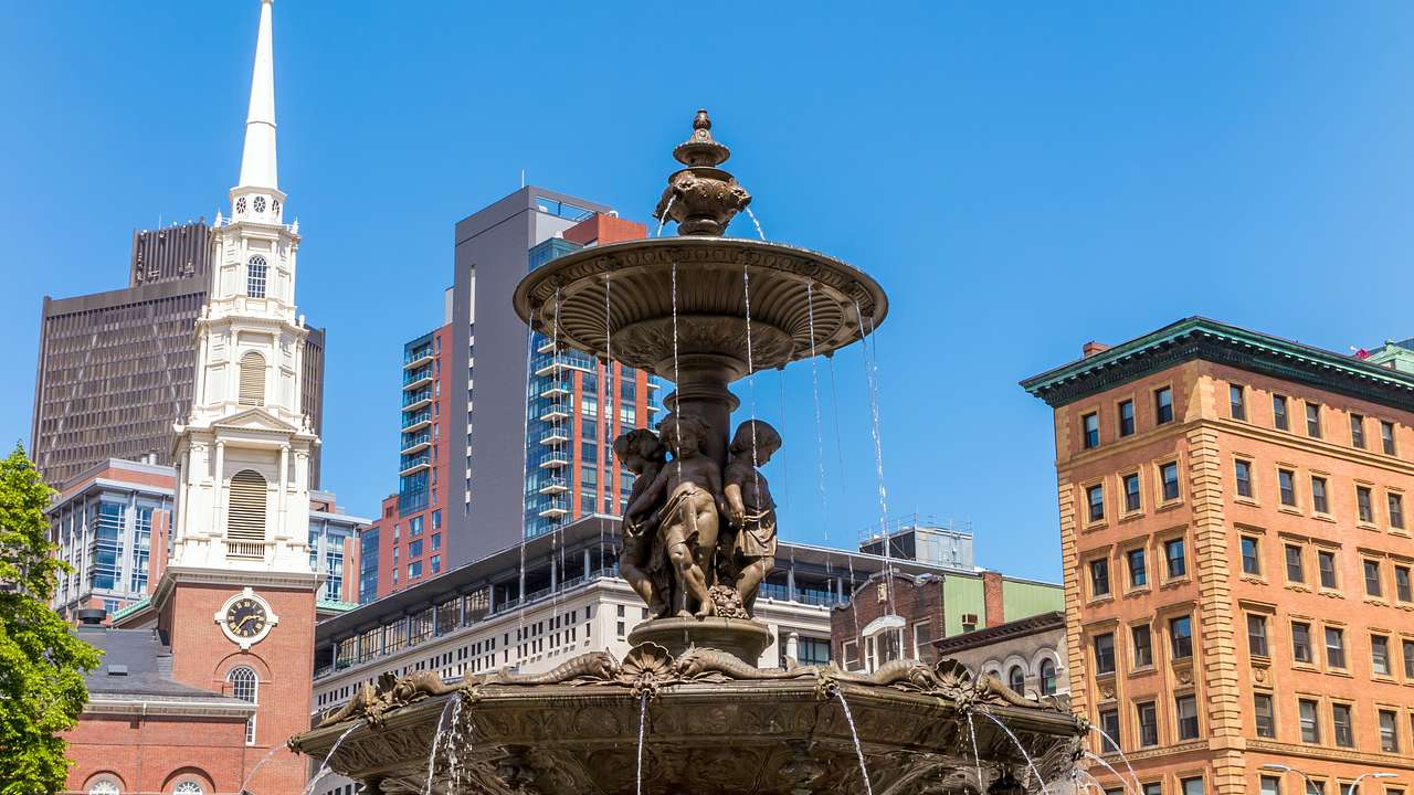 Water flowing from a fountain with buildings and blue sky around