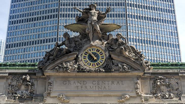 A stone Grand Central Terminal sign with clock and statue above it