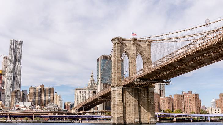 The Brooklyn Bridge suspension bridge over water with city skyline to one side