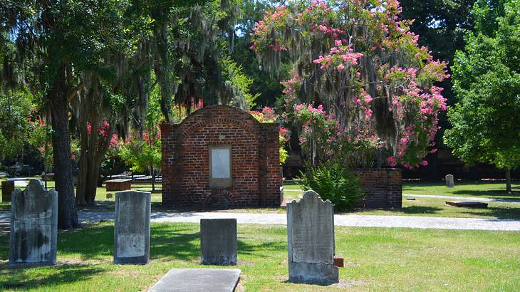 Gravestones in a cemetery on the grass with trees behind them