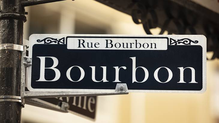 A street sign that says Bourbon and Rue Bourbon on a lamppost