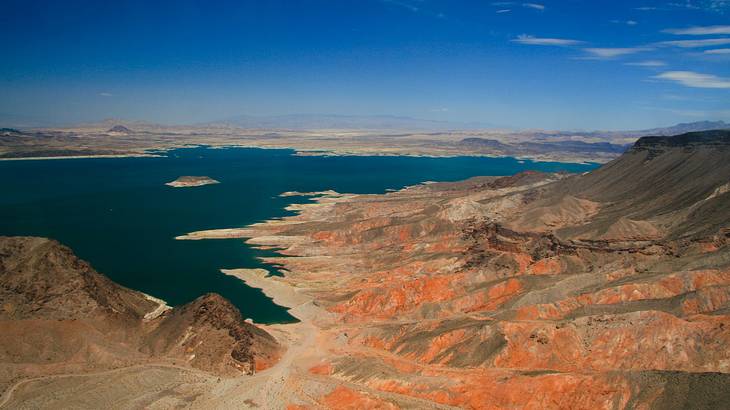 A reservoir with red rock mountains surrounding it under a blue sky A reservoir with red rock mountains surrounding it under a blue sky