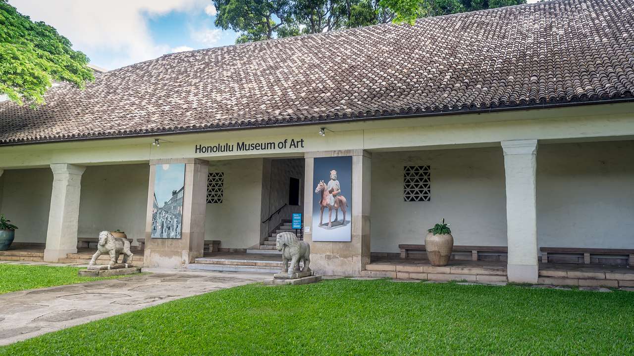 A museum building with Honolulu Museum of Art sign and statues out the front