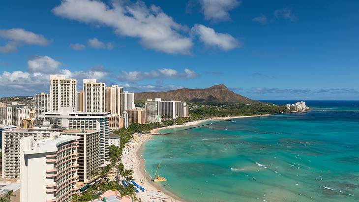 A coastal city skyline with the ocean and a beach in front of it