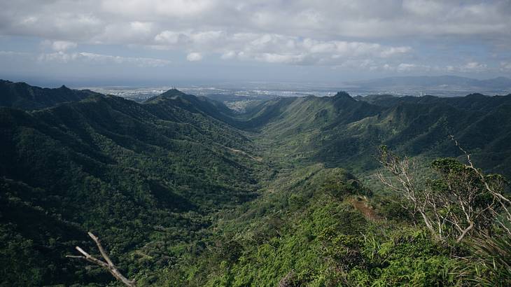 A greenery-covered mountain range under a cloudy sky