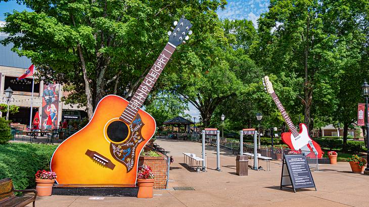 Two guitar statues on a path with trees behind them