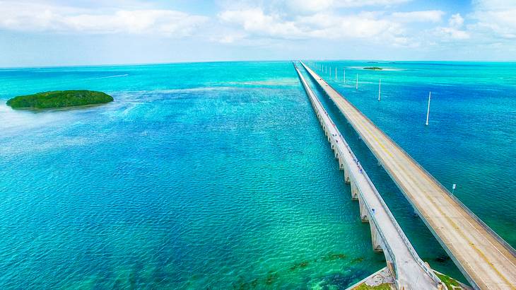 A bridge stretching over turquoise ocean with a small island to the side