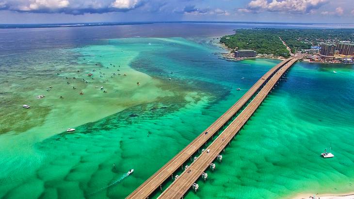 A bridge across clear ocean water with an island at the end of it