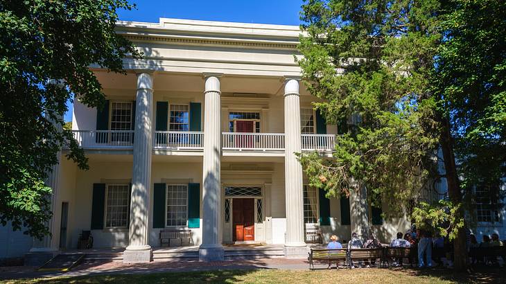 A mansion-style house with columns and grass and trees in front of it