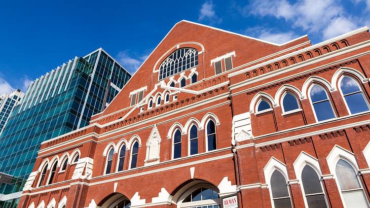 A red brick building with white details next to a high-rise building under a blue sky