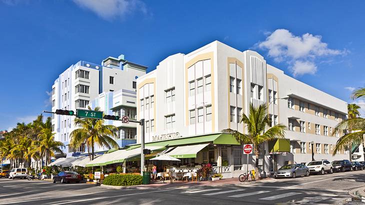 Pastel Art Deco-style buildings with a road and palm trees in front of them