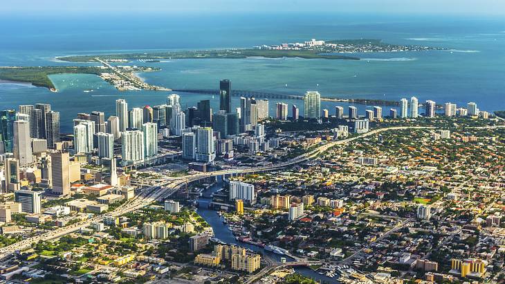 An aerial view of a city with a small island chain and water behind it