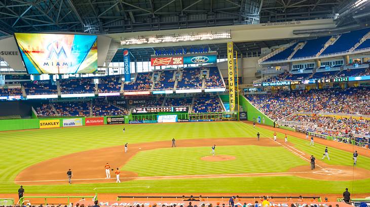 A baseball stadium with a game being played and spectators watching