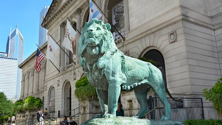 A green lion statue outside of a museum building with flags on it