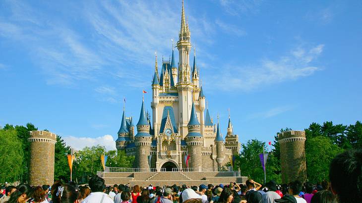 People admiring the iconic Cinderella's castle under a clear blue sky