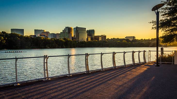 A pathway by a river with a skyline across the water at night