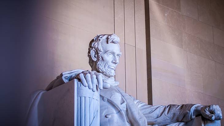 A stone statue of Abraham Lincoln sitting on a chair at dusk