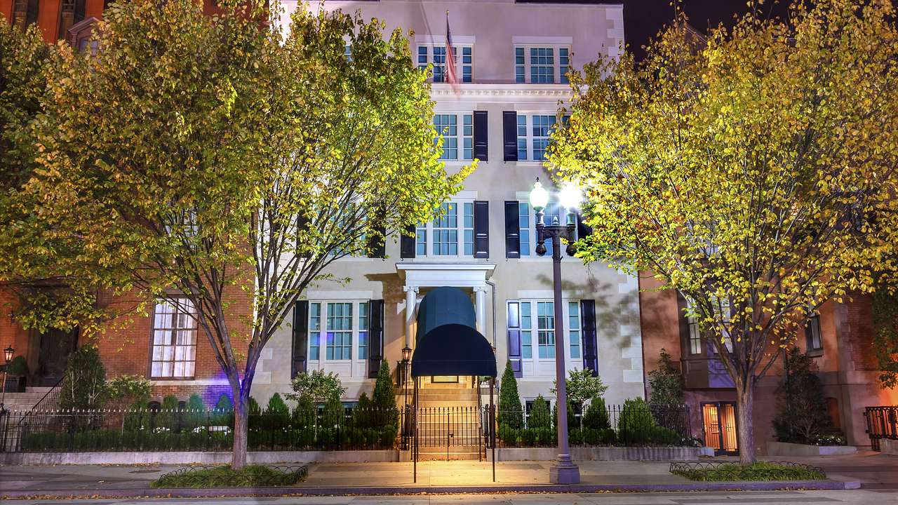 A White House with stairs to the door on a tree-lined street at night