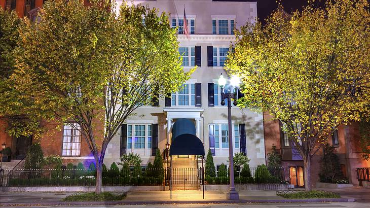 A White House with stairs to the door on a tree-lined street at night