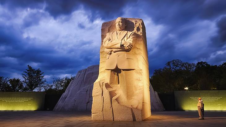 A statue of Martin Luther King Jr. with a path in front and grass behind it at night