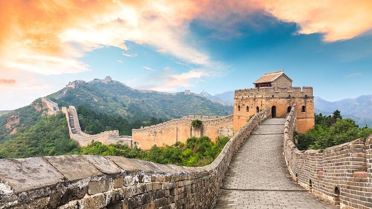 A walled walkway leading up to a building and continuing winding up a mountain