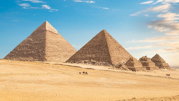 Ancient pyramids in a desert with blue sky and clouds in the background