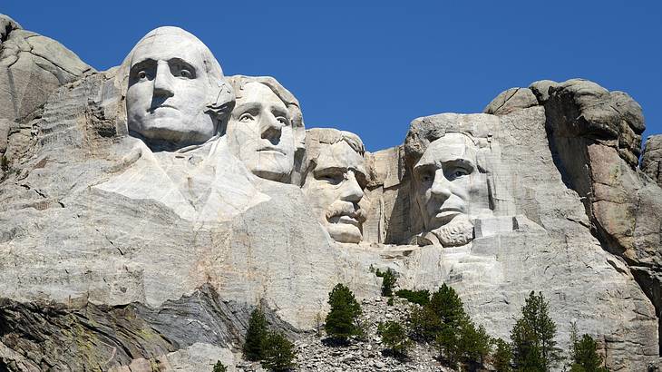 Sculptures of faces carved into a mountain against a clear blue sky