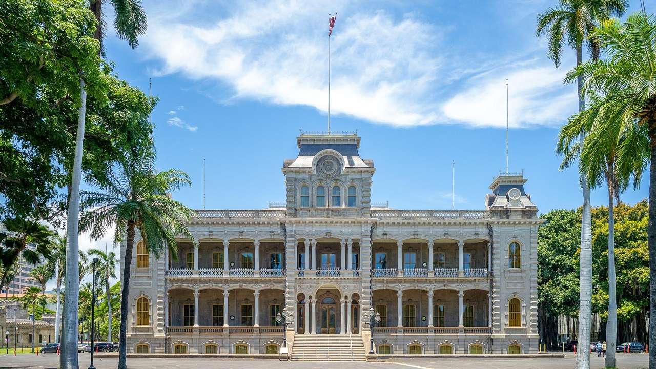 A royal palace with green grass and palm trees in front of it