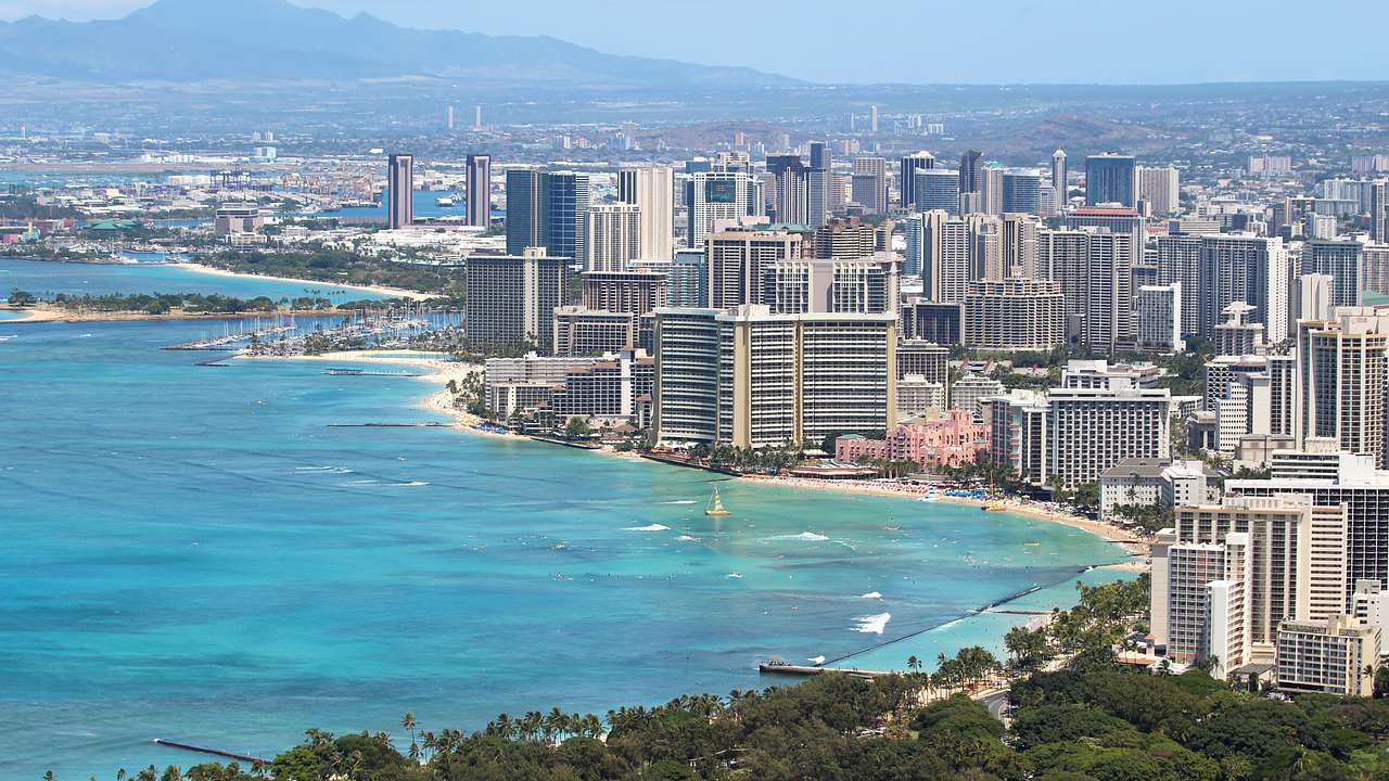 Aerial of a city skyline with the ocean in front and a mountain in the background